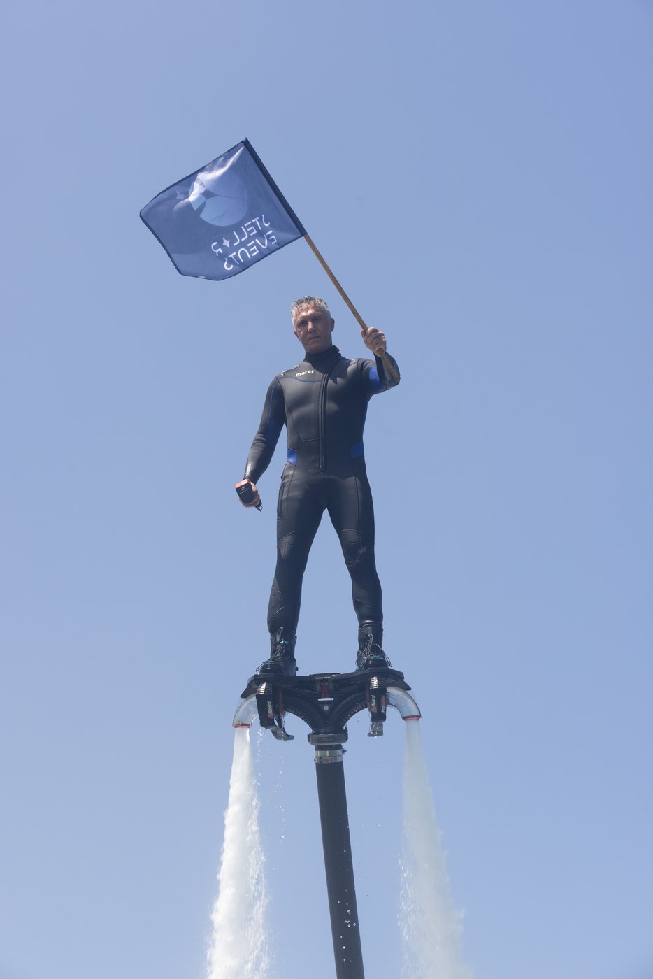Flyboarder holding a Cosmic Gate flag above the water at the Stellar experience